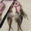 A pink dream catcher can be seen as a symbol of hope, happiness, and positivity.