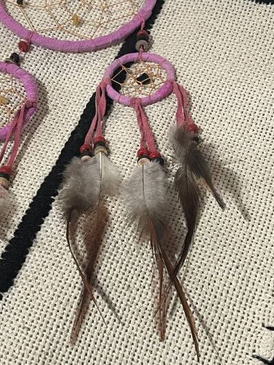 A pink dream catcher can be seen as a symbol of hope, happiness, and positivity.