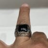 Bagues homme artisanales imposantes avec pierres noires à facettes, monture argentée et côtés gravés.