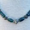 beaded-emerald-necklace-close-up orné d'un globe en argent et de perles sculptées