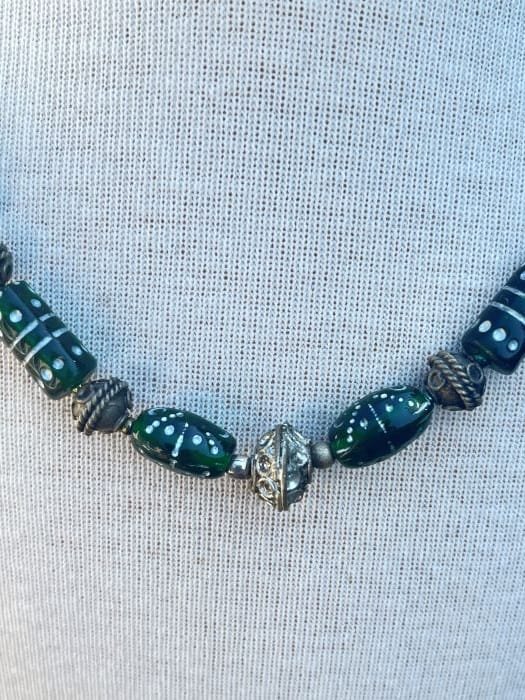 beaded-emerald-necklace-close-up orné d'un globe en argent et de perles sculptées